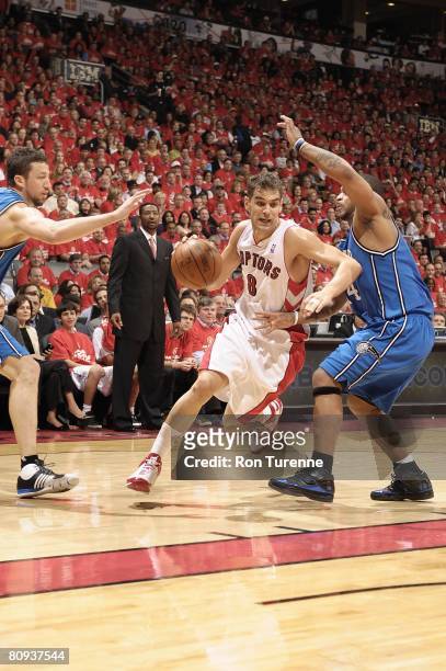 Jose Calderon of the Toronto Raptors moves the ball between Jameer Nelson and Hedo Turkoglu of the Orlando Magic in Game Three of the Eastern...