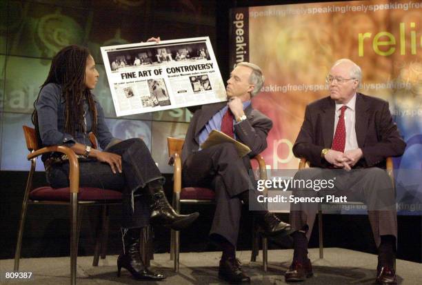 Forum moderator Ken Paulson holds up a blown-up headline during a forum on art and religion at the First Amendment Center with photographer Renee Cox...
