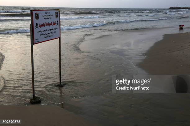Warning sign reading 'dangerous swimming and fishing' is placed near an outlet flowing sewage into the sea in front in the Shati refugee camp, in...
