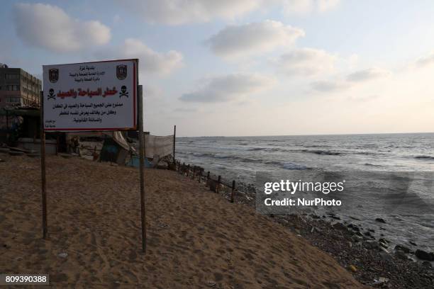 Warning sign reading 'dangerous swimming and fishing' is placed near an outlet flowing sewage into the sea in front in the Shati refugee camp, in...