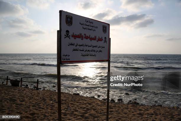 Warning sign reading 'dangerous swimming and fishing' is placed near an outlet flowing sewage into the sea in front in the Shati refugee camp, in...