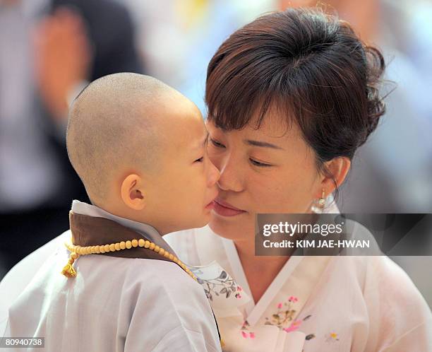 South Korean mother hugs her son after he had his head shaved sduring a ritual to celebrate Buddha's upcoming birthday on May 12 at the Chogye temple...