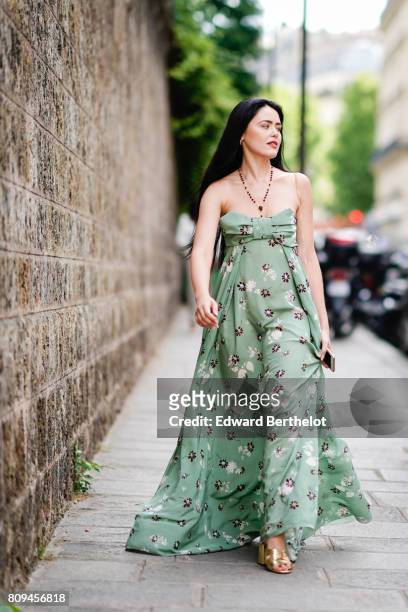Kristina Bazan wears a green off-shoulder flower print dress, a necklace, and shoes, outside the Valentino show, during Paris Fashion Week - Haute...