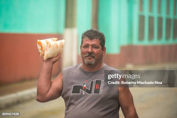 Everyday lifestyles. Cuban middle aged man carrying a milk pouches to his house.