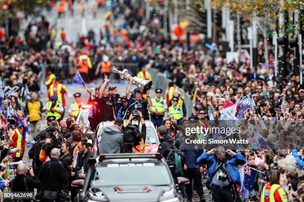 Peter Burling and Grant Dalton celebrate as Glenn Ashby holds the Americas Cup during the Team New Zealand Americas Cup Welcome Home Parade on July...