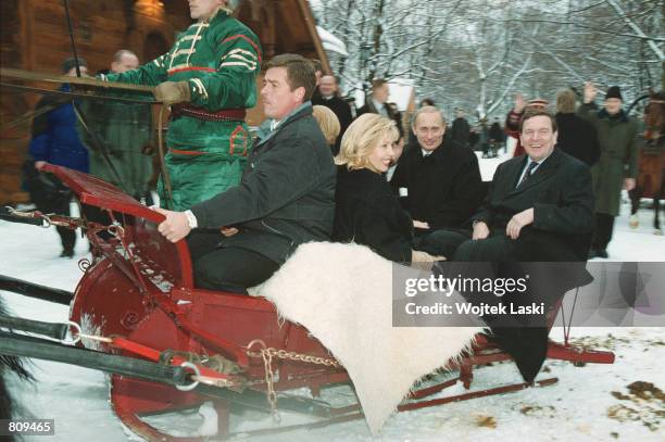 Russian President Vladimir Putin, 2nd right, rides in a troika, the traditional Russian sled pulled by three horses, with German Chancellor Gerhard...