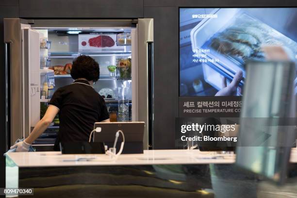 An employee cleans a Samsung Electronics Co. Refrigerator on display at the company's D'light flagship store in Seoul, South Korea, on Wednesday,...