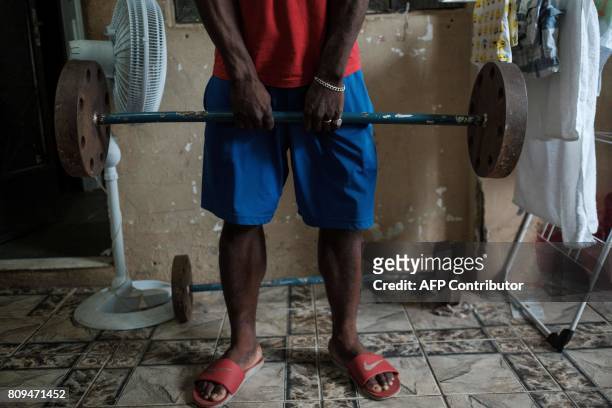 Popole Misenga, a refugee judoka from the Democratic Republic of Congo, carries hand-made 60kg weight at his home in Rio de Janeiro, Brazil, on June...