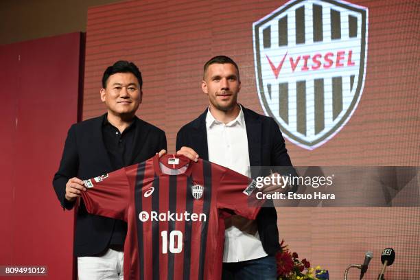 Vissel Kobe new player Lukas Podolski poses with his new jersey next to Rakuten CEO Hiroshi Mikitani during a press conference on July 6, 2017 in...