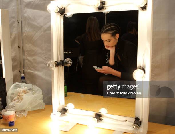 Model checks her mobile phone as she prepares backstage prior to the S&B Vie By Sass & Bide show on the fourth day of Rosemount Australian Fashion...