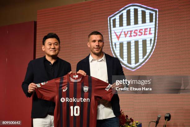 Vissel Kobe new player Lukas Podolski poses with his new jersey next to Rakuten CEO Hiroshi Mikitani during a press conference on July 6, 2017 in...