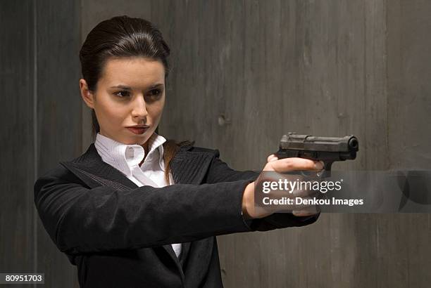 young businesswoman holding gun - business revenge stock pictures, royalty-free photos & images