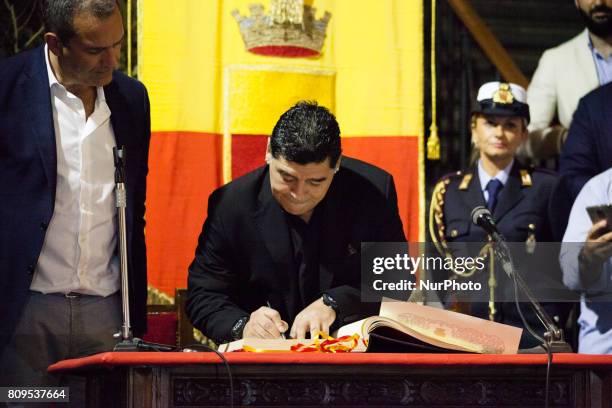 Former Argentinian football player Diego Armando Maradona signs a book as he receives the honorary citizenship of Naples from city's mayor Luigi De...