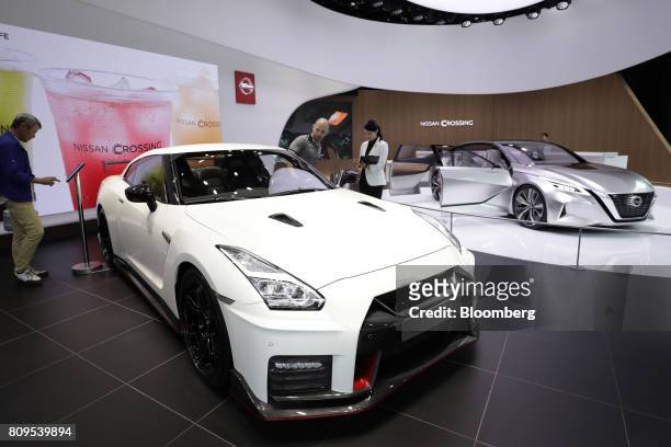Visitors look at a Nissan Motor Co. GT-R Nismo vehicle, left, on display at the company's Nissan Crossing showroom in the Ginza district of Tokyo,...