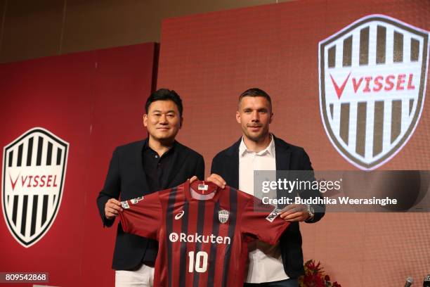 Vissel Kobe new player Lukas Podolski poses with his new jersey next to Rakuten CEO Hiroshi Mikitan during a press conference on July 6, 2017 in...