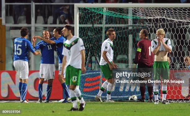 Northern Ireland players appear dejected as Italy's Federico Balzaretti celebrates scoring the third goal during UEFA Euro 2012 Qualifying match at...