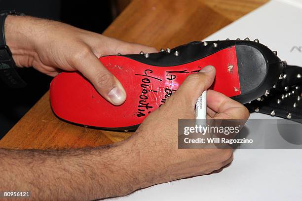 Designer Christian Louboutin signs shoes for customers at Barneys New York on May 1, 2008 in New York City.