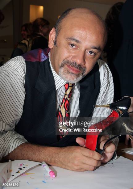 Christian Louboutin signs shoes for customers at Barneys New York on May 1, 2008 in New York City.