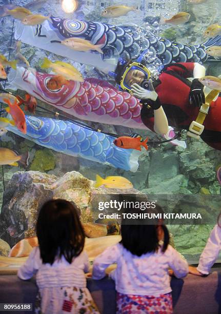 Female diver waves beside the carp-shaped streamers during the feeding show to celebrate the upcoming Children's Day at the SunShine International...