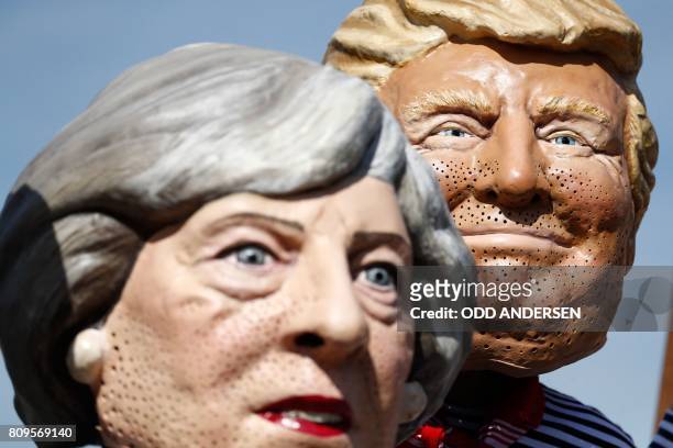 Anti-capitalism activists wearing masks of Britain's Prime Minister Theresa May and US President Donald Trump protest on July 6, 2017 in Hamburg,...