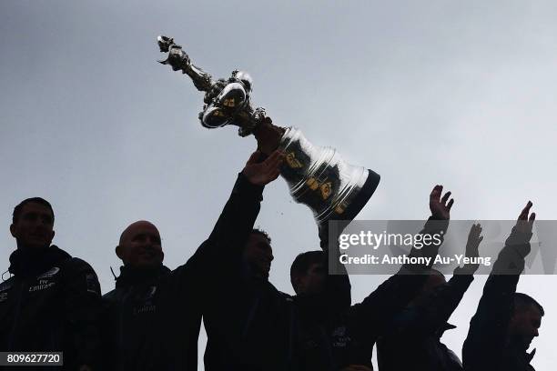 Members of Emirates Team New Zealand lift the America's Cup trophy in celebration during the Team New Zealand Americas Cup Welcome Home Parade on...