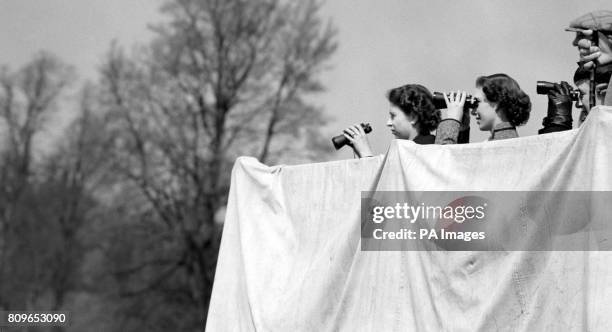 Queen Elizabeth II, Princess Margaret and the Princess Royal , level their binoculars on a competitor as they watch from a farm cart grandstand, the...