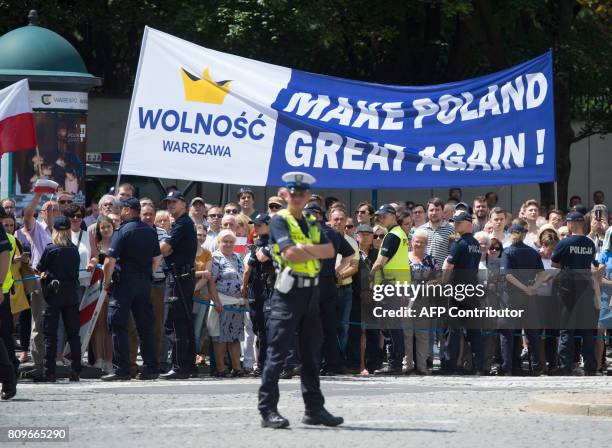 Demonstrators hold a banner reading "make poland great again" as US President Donald Trump gives a speech in front of the Warsaw Uprising Monument on...