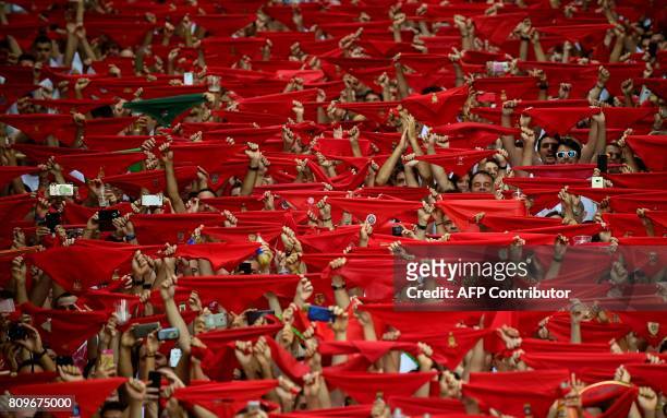 Participants hold red scarves as they celebrate the 'Chupinazo' to mark the kickoff at noon sharp of the San Fermin Festival, in front of the Town...