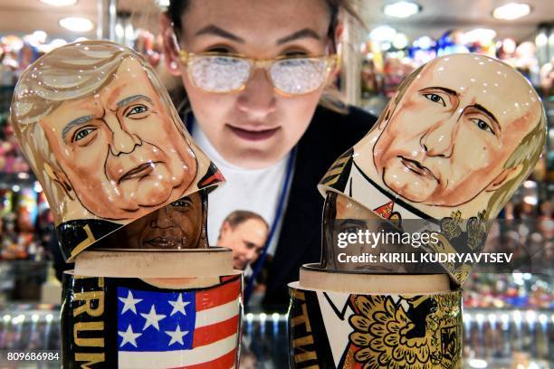 Woman looks at traditional Russian wooden nesting dolls, called Matryoshka dolls, depicting US President Donald Trump and Russia's President Vladimir...