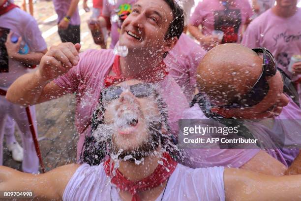 Revellers are soaked with water poured from balconies as they celebrate the 'Chupinazo' to mark the kickoff at noon sharp of the San Fermin Festival,...