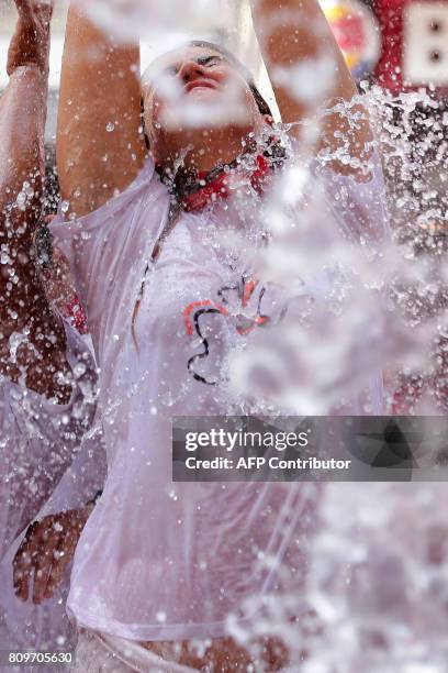 Reveller is soaked with water poured from balconies as they celebrate the 'Chupinazo' to mark the kickoff at noon sharp of the San Fermin Festival,...