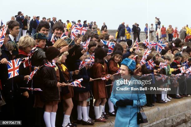 Queen Elizabeth II walks past flag waving schoolchildren on her arrival on the island of Alderney, Channel Islands.