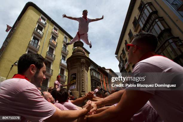 Reveller jumps from a fountain at Navarreria Street as people enjoy the atmosphere during the opening day or 'Chupinazo' of the San Fermin Running of...