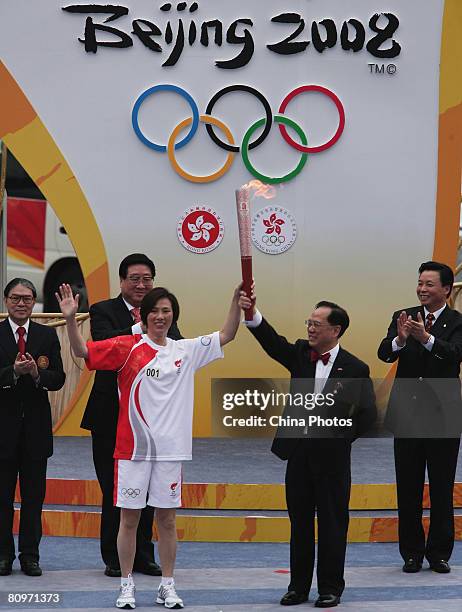 Hong Kong Chief Executive Donald Tsang hands over the Olympic torch to the first torchbearer in Hong Kong, Olympic gold medallist, windsurfer Lee Lai...