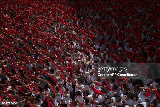 Participants hold red scarves as they celebrate the 'Chupinazo' to mark the kickoff at noon sharp of the San Fermin Festival, in front of the Town...