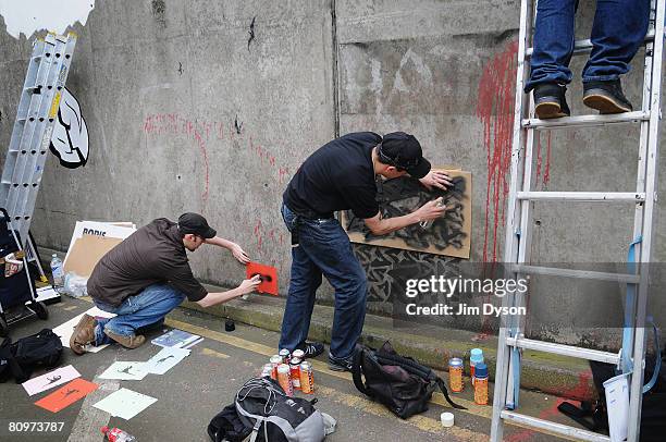 Stencil artists paint the walls of a subway as a giant new exhibition space created by famed graffiti artist Banksy opens to the public on May 3,...