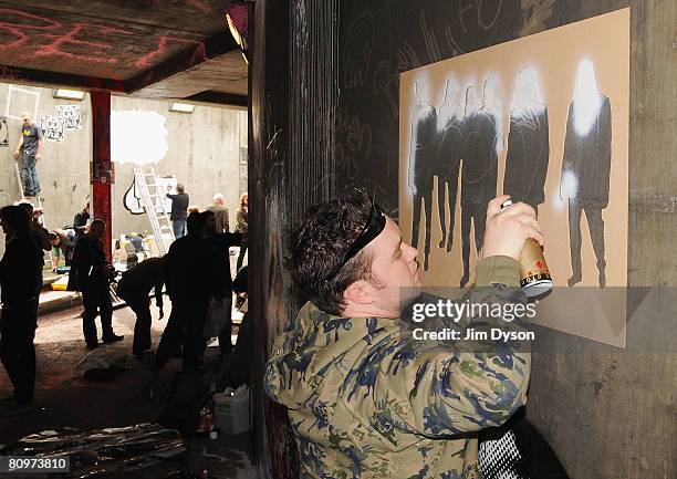 Stencil artists paint the walls of a subway as a giant new exhibition space created by famed graffiti artist Banksy opens to the public on May 3,...