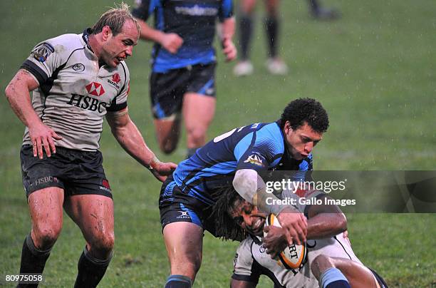 Lote Tuqiri of Waratahs is tackled by Zane Kirchner of Blue Bulls as Phil Waugh looks on during the Super 14 match between Vodacom Blue Bulls and...