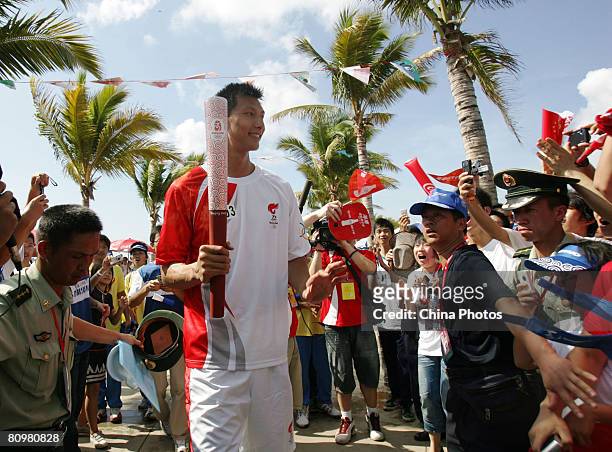 Chinese NBA basketball player Yi Jianlian carries the Olympic Torch during the Sanya leg of Beijing Olympic torch relay on May 4, 2008 in Sanya of...