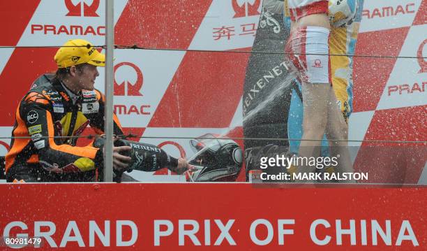 Finnish rider Mika Kallio from Team Red Bull KTM sprays champagne on a pit girl as he celebrates on the podium after winning the 250cc race at the...