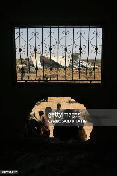 Palestinians gather to inspect the damage done to a home as a demolished house sits in the background following an Israeli operation in the Southern...