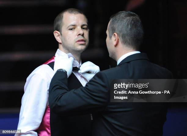 England's Barry Hawkins has his bow tie adjusted by referee Terry Camilleri during his first round match of the Betfred.com World Snooker...