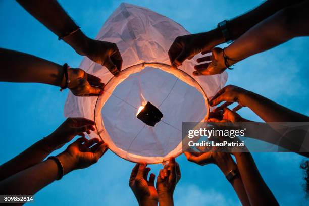 amici che illuminano una lanterna di carta alla festa - chinese lantern foto e immagini stock