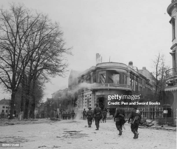 Brithish troops in Arnhem next smouldering buildings.