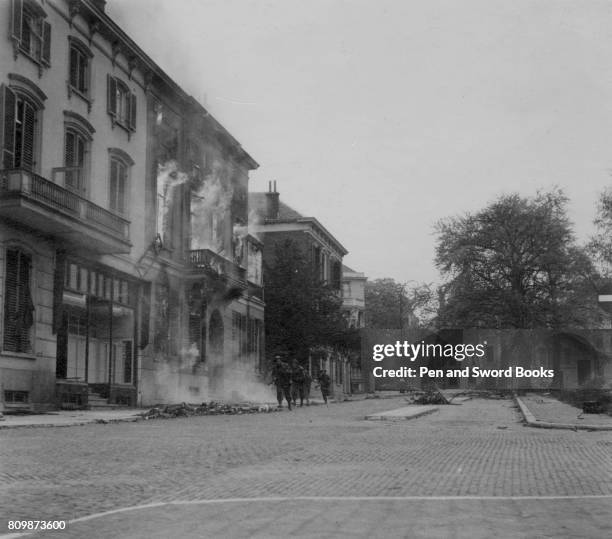 British troops in Arnhem running through burning street.