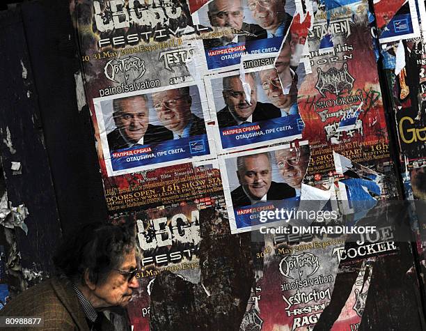 An elderly woman passes by pre-election posters showing Vojislav Seselj , leader of the hard-line nationalist Serbian Radical Party, and his deputy...