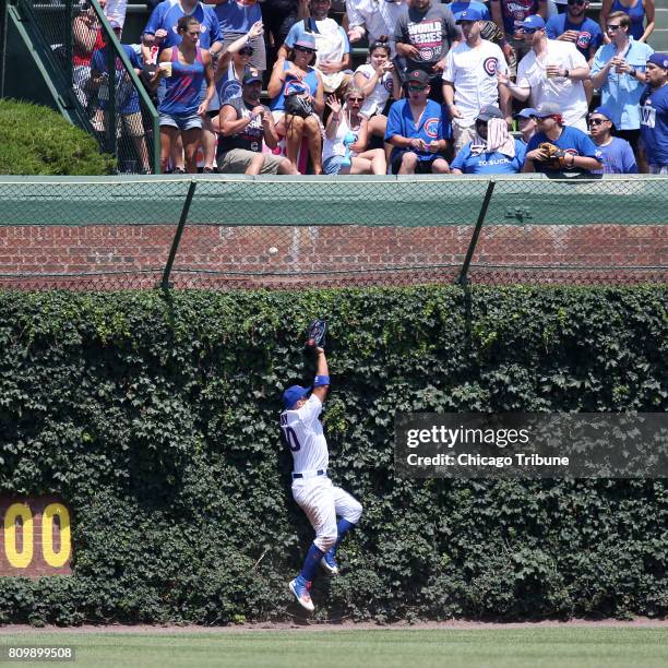 Chicago Cubs left fielder Jon Jay runs into the ivy while chasing a two-run home run ball hit by Milwaukee Brewers left fielder Ryan Braun in the...