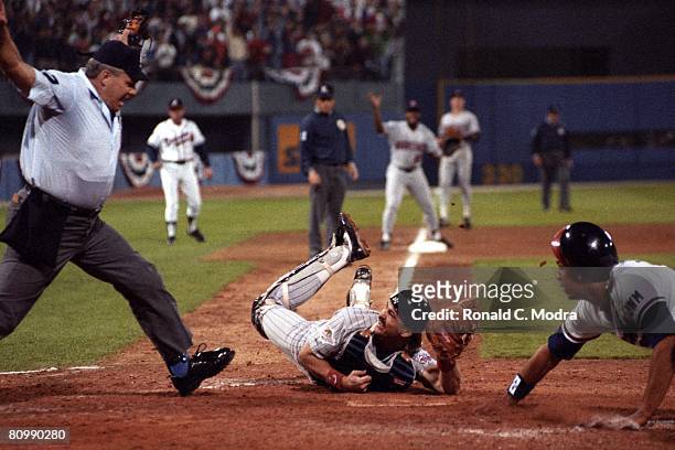 David Justice of the Atlanta Braves scores as Brian Harper of the Minnesota Twins tries to tag him during Game 3 of the 1991 World Series on October...