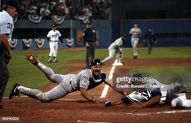 David Justice of the Atlanta Braves scores as Brian Harper of the Minnesota Twins tries to tag him during Game 3 of the 1991 World Series on October...