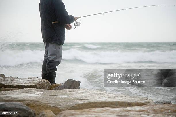 fisherman fishing in stormy sea - dique fotografías e imágenes de stock